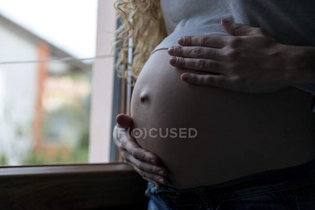 Young pregnant woman touching abdomen at home — Stock Photo