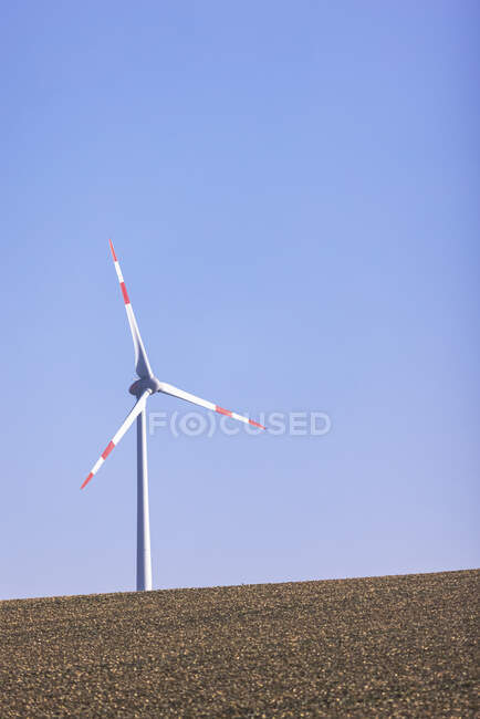 Ветряная турбина стоит на фоне ясного голубого неба — стоковое фото