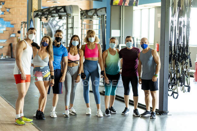 Sportlerinnen und Sportler mit Mundschutz stehen im Fitnessstudio — Stockfoto