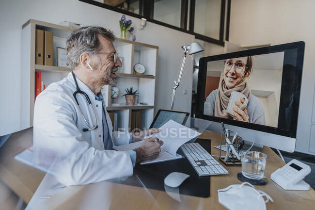 Operatore sanitario che parla con il paziente tramite videochiamata al computer presso lo studio del medico — Foto stock