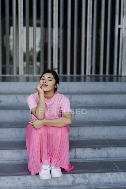 Женщина с рукой на подбородке сидит на ступеньках — стоковое фото