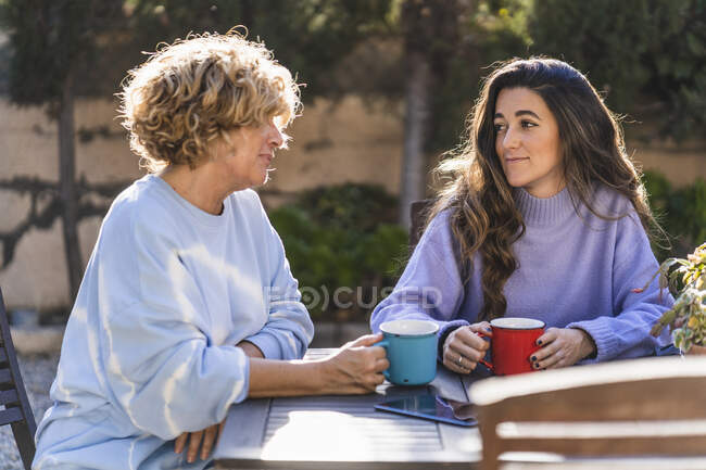 Donna matura che parla con giovane femmina mentre si siede nel cortile posteriore — Foto stock