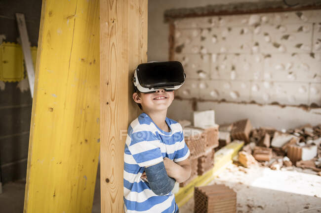 Мальчик со сломанной рукой с гарнитурой виртуальной реальности в квартире на чердаке — стоковое фото