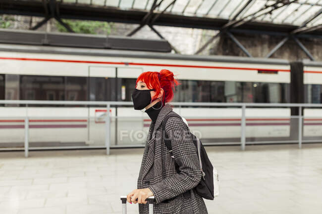 Redheaded woman wearing protective face mask at railroad station — Stock Photo