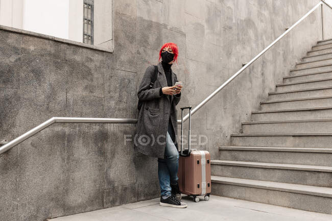 Rothaarige Frau wartet mit Gepäck auf Stufen — Stockfoto