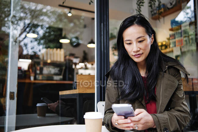 Woman using mobile phone at cafe — Stock Photo