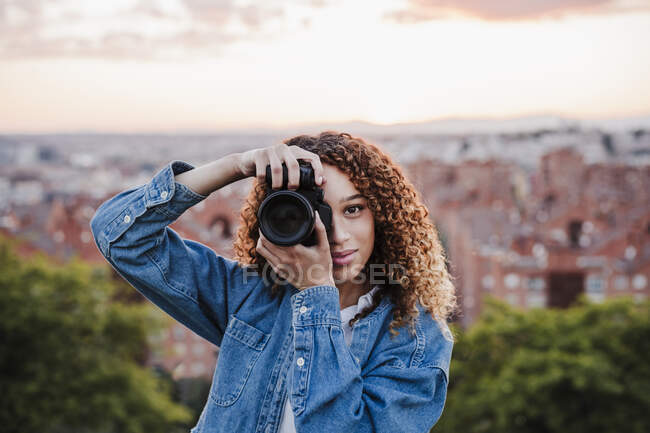 Fotografo sorridente femminile che scatta foto nel parco — Foto stock