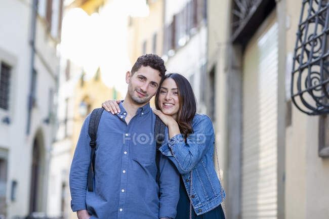 Пара улыбается, стоя вместе на городской улице — стоковое фото