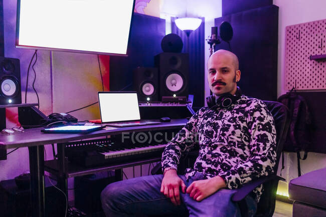 Compositeur masculin assis par des équipements audio en studio — Photo de stock