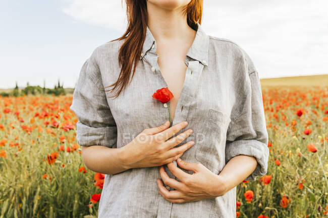 Mulher segurando flor de papoula vermelha enquanto está no campo — Fotografia de Stock