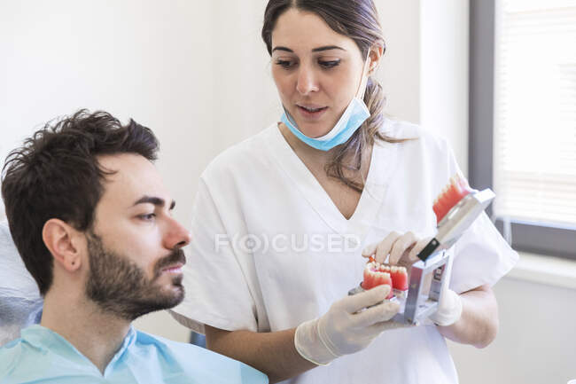 Dentista femminile che spiega il modello di denti al paziente presso la clinica medica — Foto stock