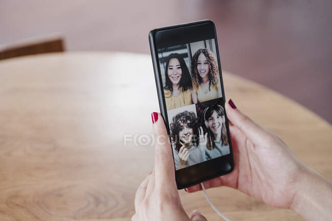 Молода жінка розмовляє з подругами під час відео через смарт-телефон у кав'ярні. — стокове фото