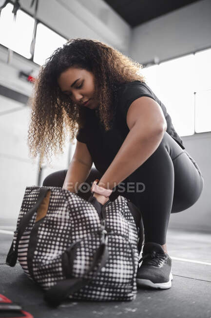 Curly atleta cabelo cabeludo feminino com saco no ginásio — Fotografia de Stock