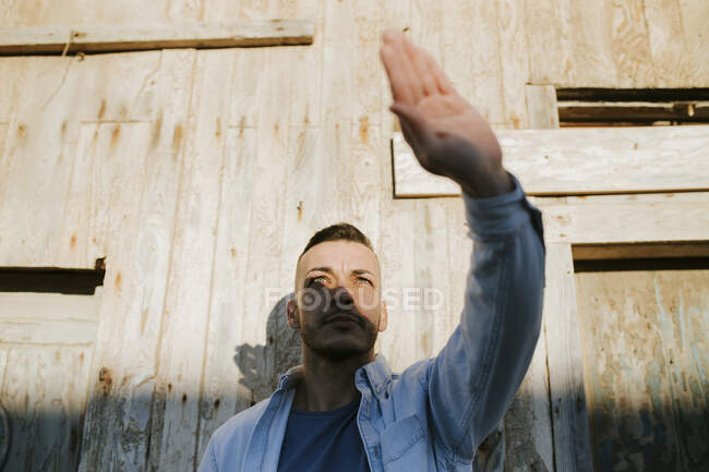 Mann schirmt sein Gesicht durch die Hand vor Sonnenlicht ab, während er gegen Wand steht — Stockfoto