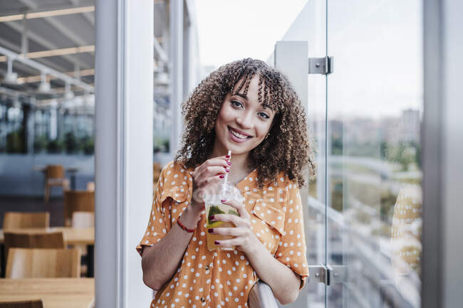 Bella donna con frangia che beve in tazza usa e getta al balcone della caffetteria — Foto stock