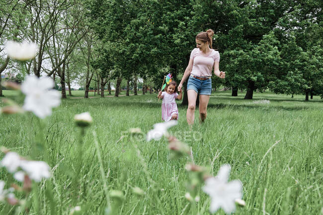 Ragazza che tiene girandola mentre cammina con la madre al parco — Foto stock