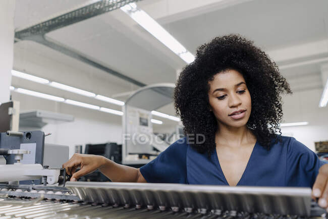 Afro businesswoman adjusting machinery at printing industry — Stock Photo
