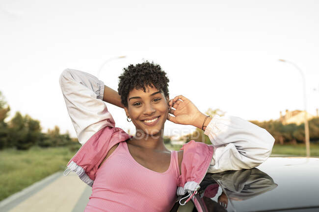 Посміхнена жінка з головою в руках біля машини. — стокове фото