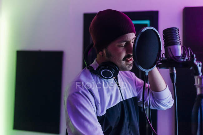 Homme portant un chapeau en tricot chantant au home studio — Photo de stock