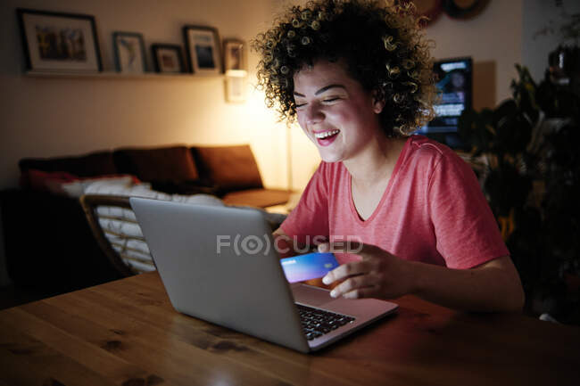 Весела молода жінка з ноутбуком робить покупки вдома. — стокове фото