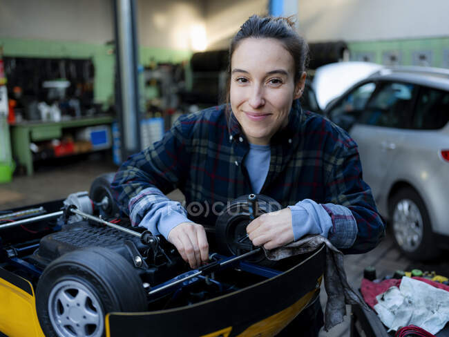 Meccanica femminile che lavora su auto giocattolo in officina — Foto stock