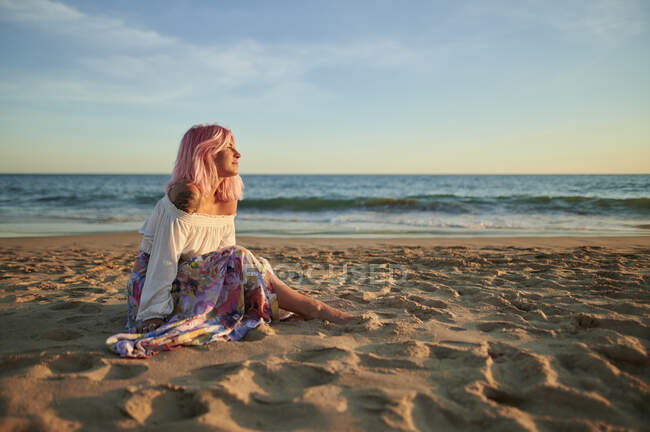 Giovane donna contemplando mentre seduto sulla sabbia in spiaggia — Foto stock
