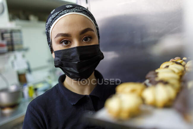 Femme propriétaire portant un masque protecteur dans la boulangerie — Photo de stock