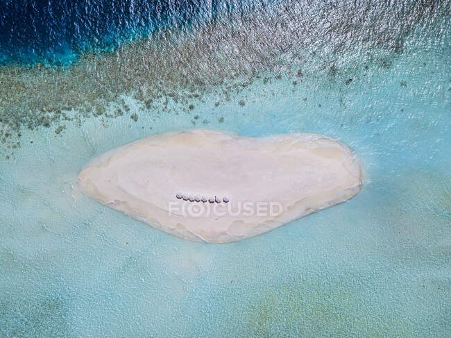Vista aérea de sombrillas de playa en un pequeño islote arenoso frente a la costa del Océano Índico en verano - foto de stock