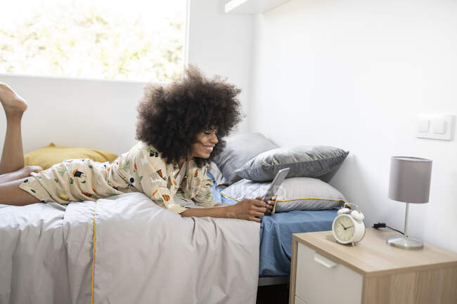 Woman using digital tablet while lying on bed at home — Stock Photo