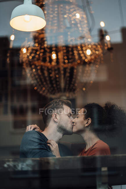 Boyfriend and girlfriend kissing each other while sitting at cafe — Stock Photo
