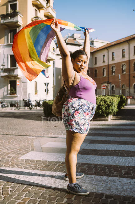 Attivista donna protesta con bandiera arcobaleno sulla strada — Foto stock