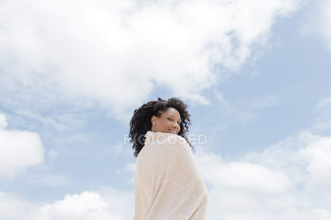 Mulher sorridente envolta em toalha no dia ensolarado — Fotografia de Stock