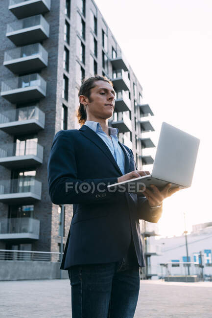 Empresario usando portátil mientras está de pie en la ciudad - foto de stock