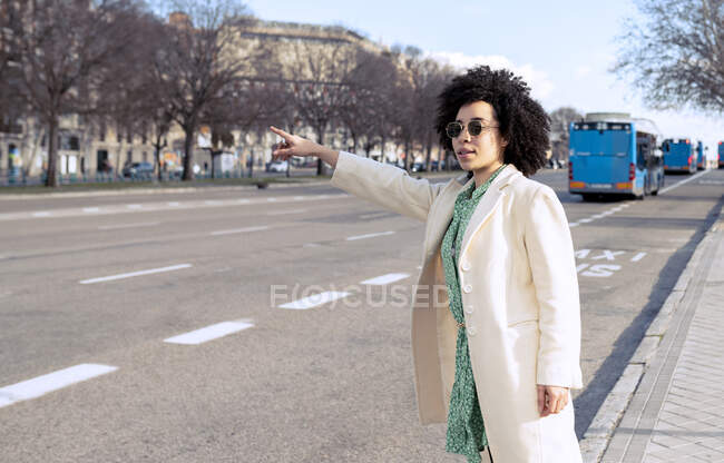 Молода жінка з сонцезахисними окулярами під час їзди стоячи біля стежки в місті. — стокове фото