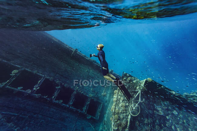 Junger Mann in Taucherflossen schwimmt bei Schiffbruch im Meer — Stockfoto