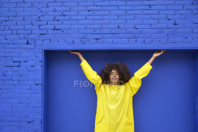 Jeune femme afro avec les yeux fermés devant le mur bleu — Photo de stock
