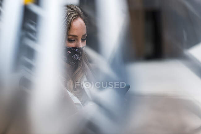 Geschäftsfrau mit Schutzmaske durch Glasfenster gesehen — Stockfoto