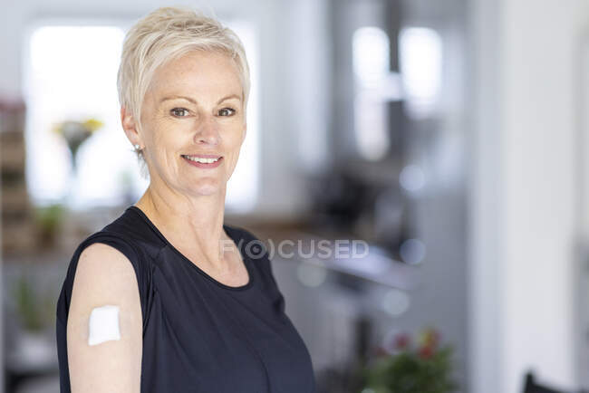 Donna matura con benda sulla spalla dopo la vaccinazione a casa — Foto stock