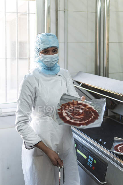 Employee holding package of meat in factory — Stock Photo