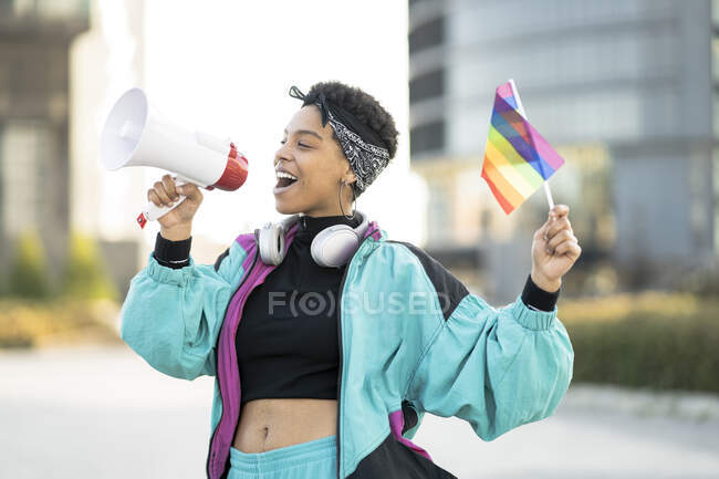 Жіночий протестувальник ЛГБТКІЇ тримає прапор веселки, оголошуючи через мегафон. — стокове фото