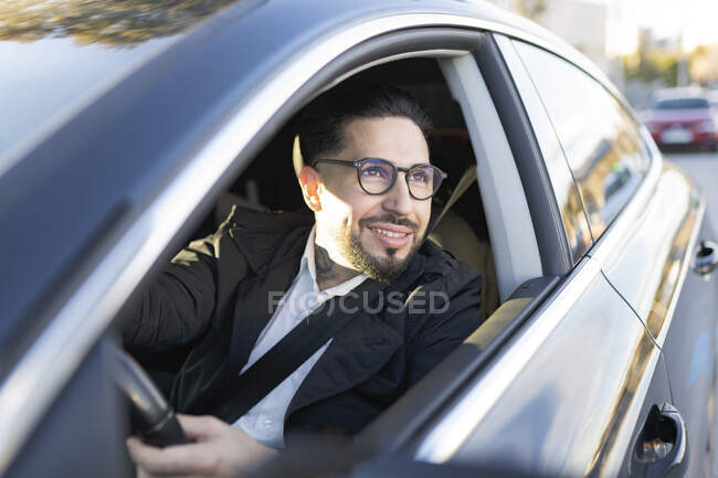 Empresário sorrindo olhando para longe durante a condução de carro — Fotografia de Stock