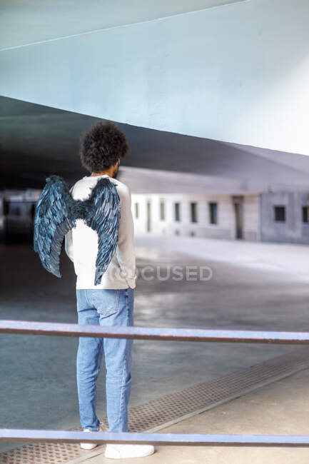 Mann mit Engelsflügeln steht vor Gebäude — Stockfoto