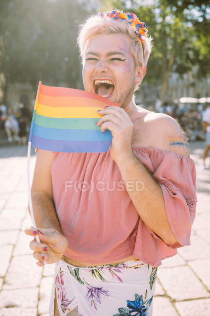 Feliz gay homem rindo com arco-íris bandeira no ensolarado dia — Fotografia de Stock