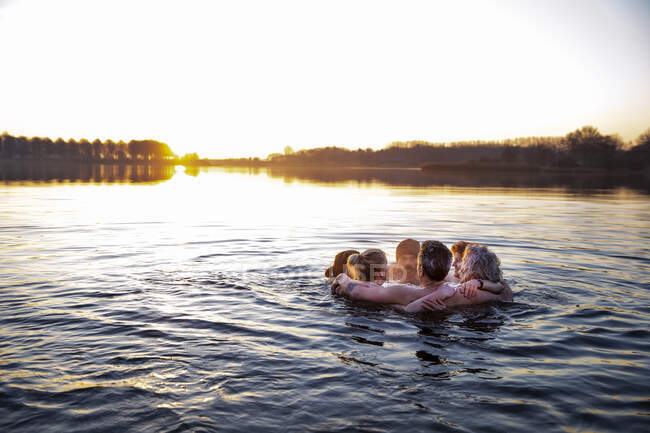 Amis masculins et féminins avec les bras autour de parler dans l'eau — Photo de stock