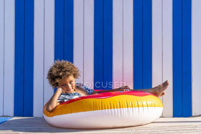 Mignon garçon assis dans un beignet gonflable multicolore — Photo de stock
