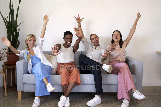 Мужчины и женщины-коллеги радуются, сидя на диване — стоковое фото