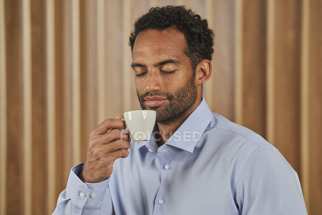 Businessman smelling coffee scent from cup in board room — Stock Photo