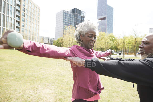 Uomo che assiste la donna anziana nell'esercizio al parco — Foto stock