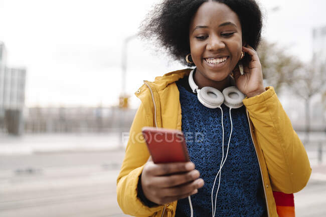 Donna sorridente in abiti caldi utilizzando il telefono cellulare — Foto stock
