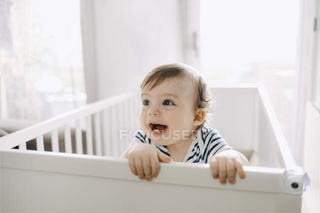 Cute baby boy looking away in crib at home — Stock Photo
